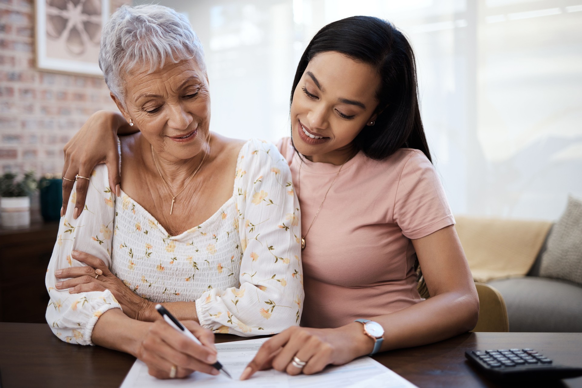 Shot of a young woman going over paperwork with her elderly mother at home