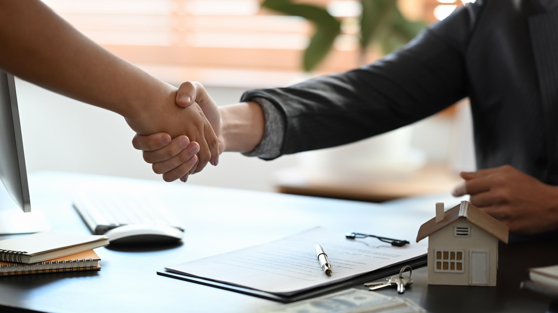 Young woman handshaking with real estate agent after signing contract.